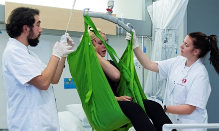 Verpleegkundige helpt een patiënt met een tillift